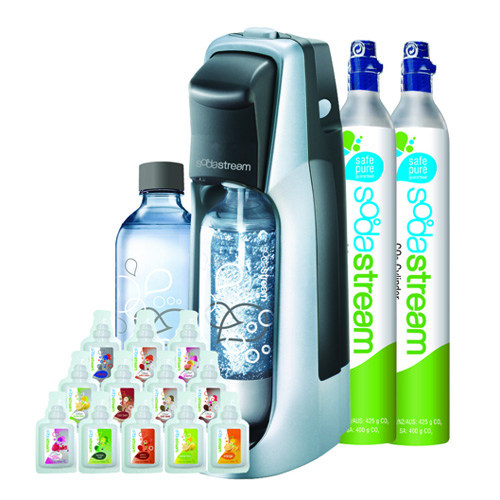 Soda machine with a clear carbonating bottle, two CO2 canisters, and various flavor syrup bottles arranged in front. The canisters and soda machine both read SodaStream with graphic designs of bubbles on them.