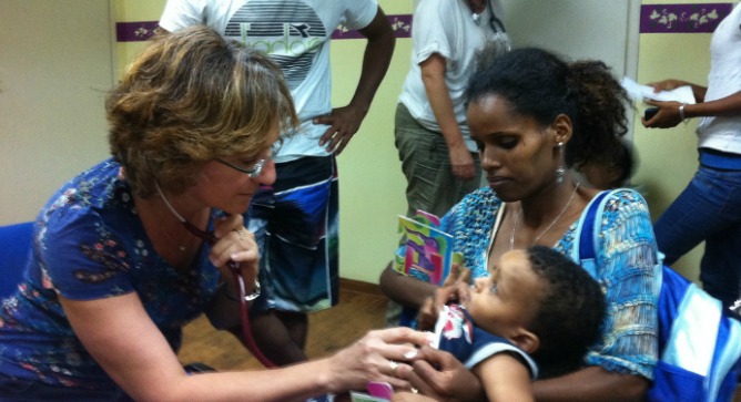 A physician at the Israel Health Ministry’s clinic for refugees treating a patient, as an Eritrean nurse (in T-shirt and shorts) stands ready to translate.
