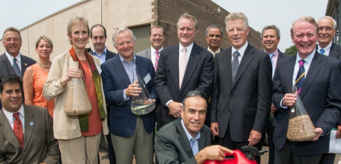 Primus Green Energy Chairman Dr. Yom-Tov Samia (front middle) with guests including former New Jersey Governor Jim Florio at the company's demo plant dedication. The beakers contain wood pellet feedstock and Primus' 93-octane gasoline.
