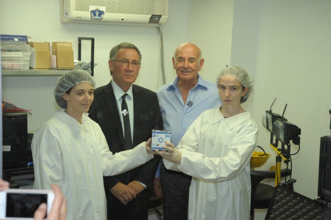Minister of Science, Technology and Space Yaakov Peri, Herzliya Mayor Moshe Fadlon, and two Herzliya students show a model of the satellite. (Avshalom Shoshani)