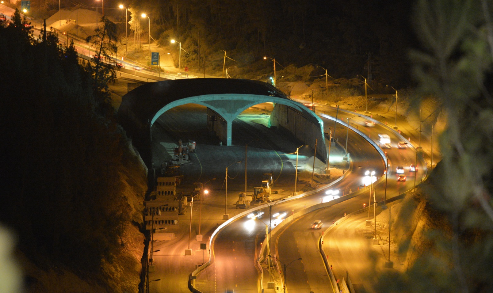 A view of the Highway 1 eco-bridge at night. When the new road is completed, the winding lanes seen to the right will be rerouted under the bridge. Photo courtesy of Netivei Israel