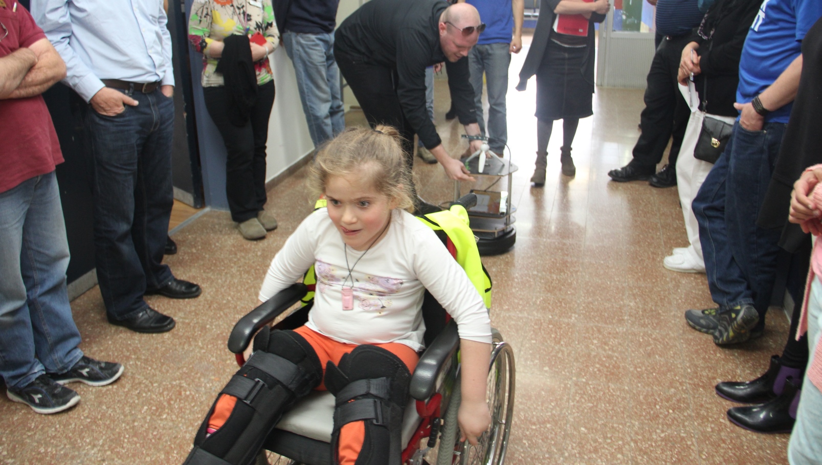 This robotic helper carries items as it follows a child in a wheelchair. Photo courtesy of ALYN