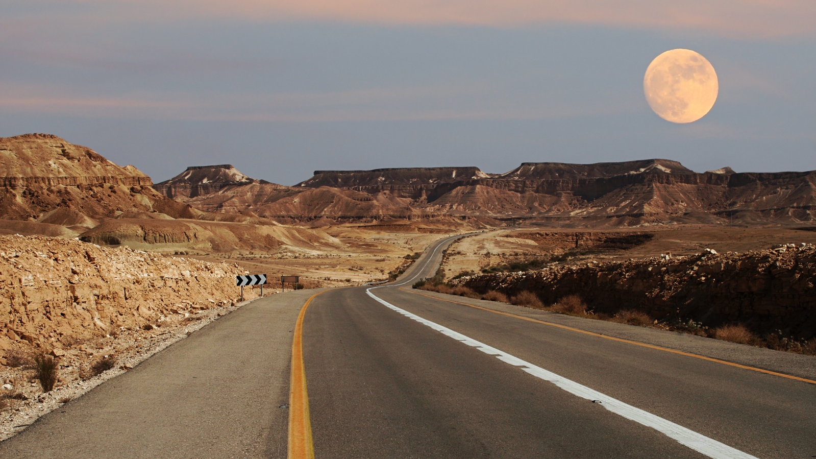 Moon rising over the road running through the Ramon Crater. Photo by Rostislav Glinsky/Shutterstock.com