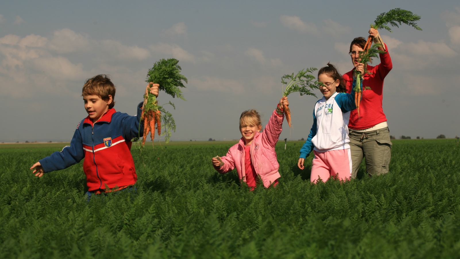 Children hold up freshly dug carrots from a field in the Western Negev. Photo by Doron Horowitz/FLASH90