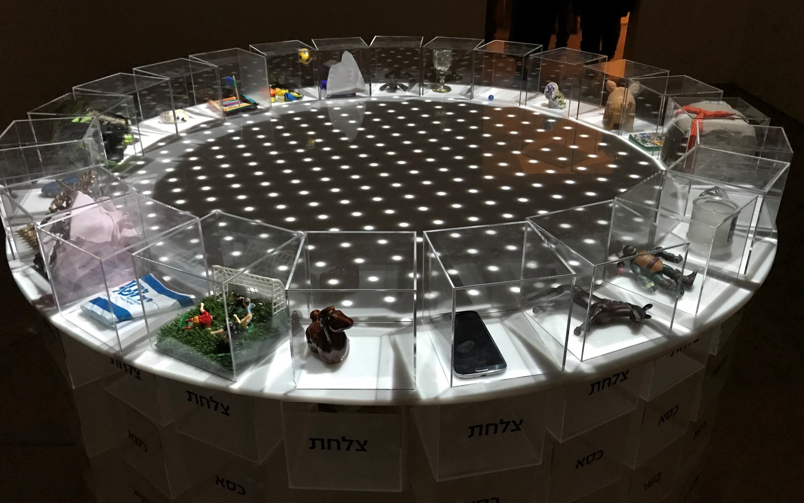 Personal objects in Perspex boxes make up this festive dinner table to symbolize human organization. Photo by Naama Barak