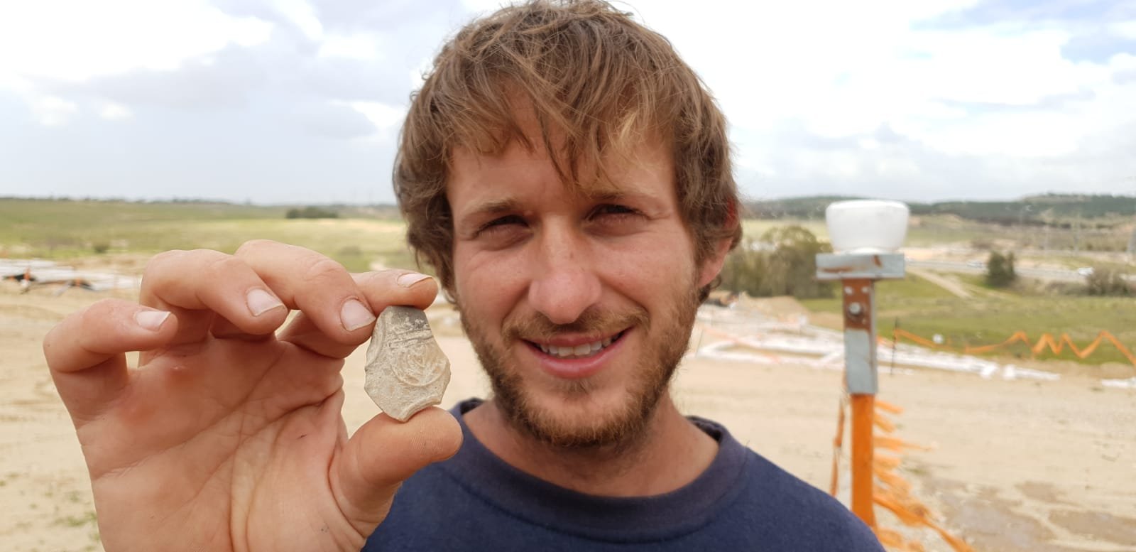IAA Archaeologist Avinoam Lehavi holding the ancient oil lamp sherd decorated with a menorah. Photo by Anat Rasiuk/Israel Antiquities Authority
