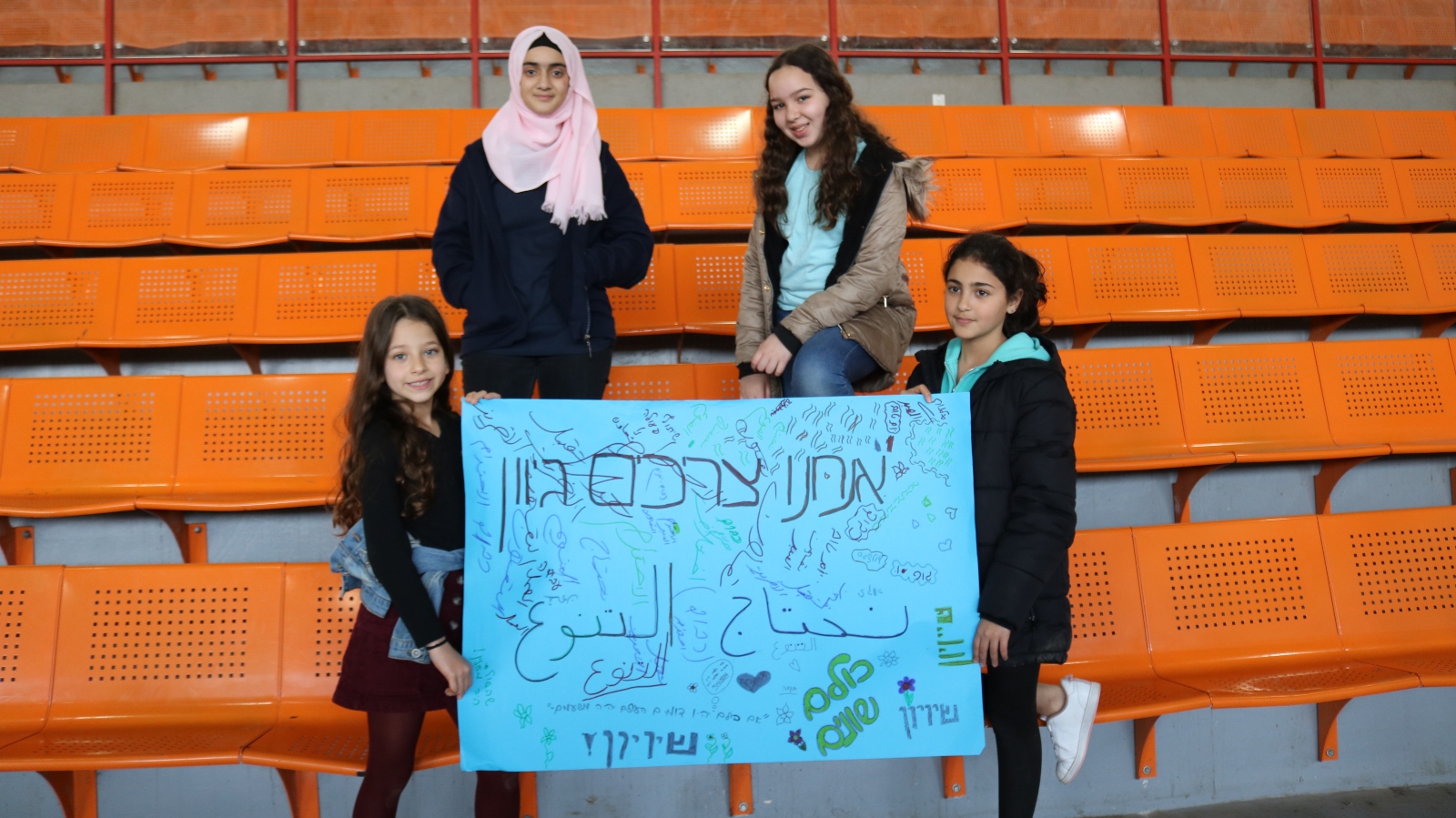 Children in the Arab village of Kalansua with a poster stating: "We need diversity” and “We are all equal” in Hebrew and Arabic. Photo courtesy of the Peres Center