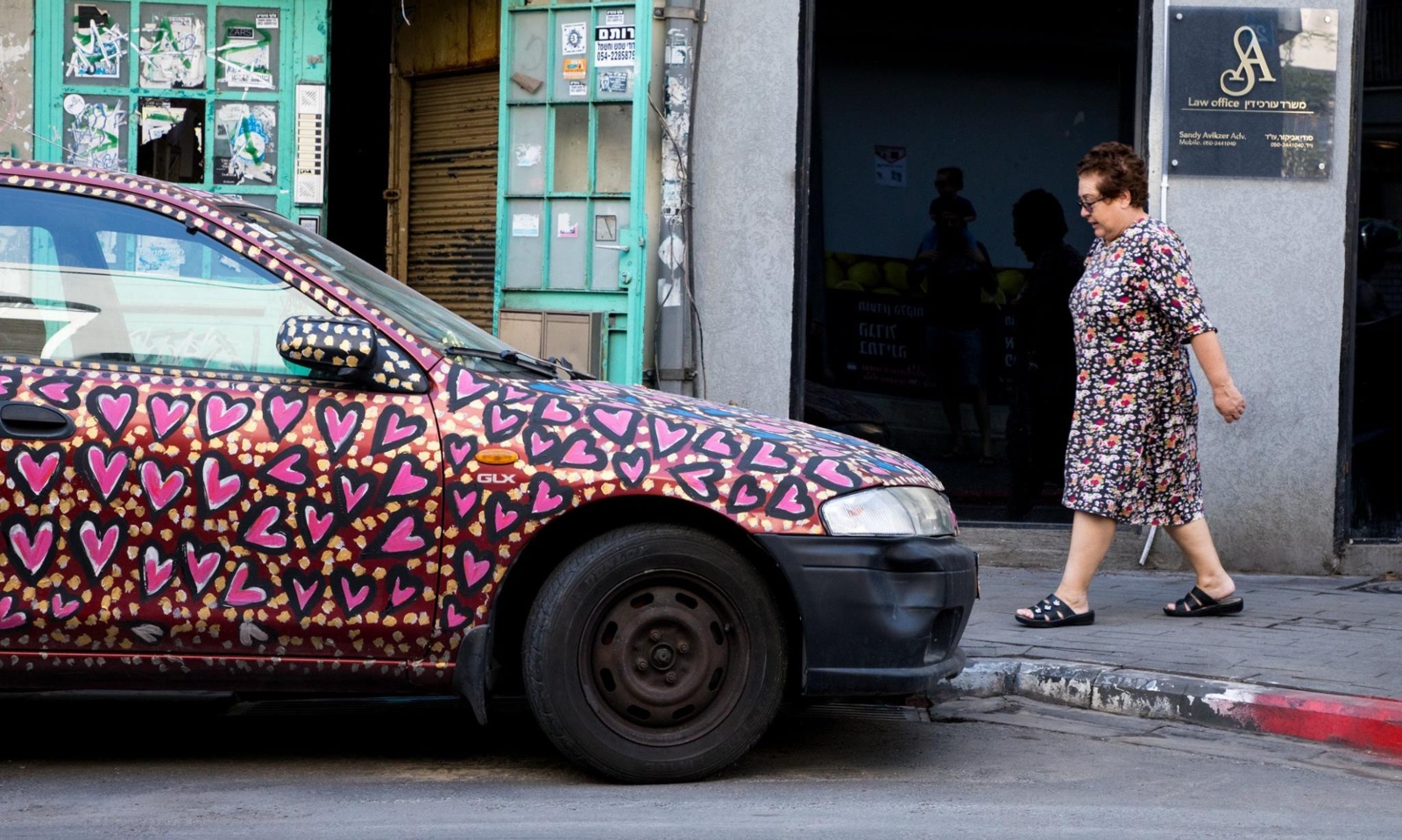 A pedestrian’s dress complements a painted car. Photo by Evyatar Dayan/ThisIsTelAviv