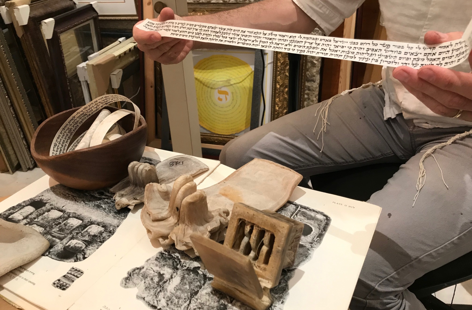 Jamie Shear shows tefillin scrolls he wrote and leather tefillin boxes that look strikingly similar to 2,300-year-old tefillin found in the Dead Sea caves (pictured in book). Photo by Abigail Klein Leichman