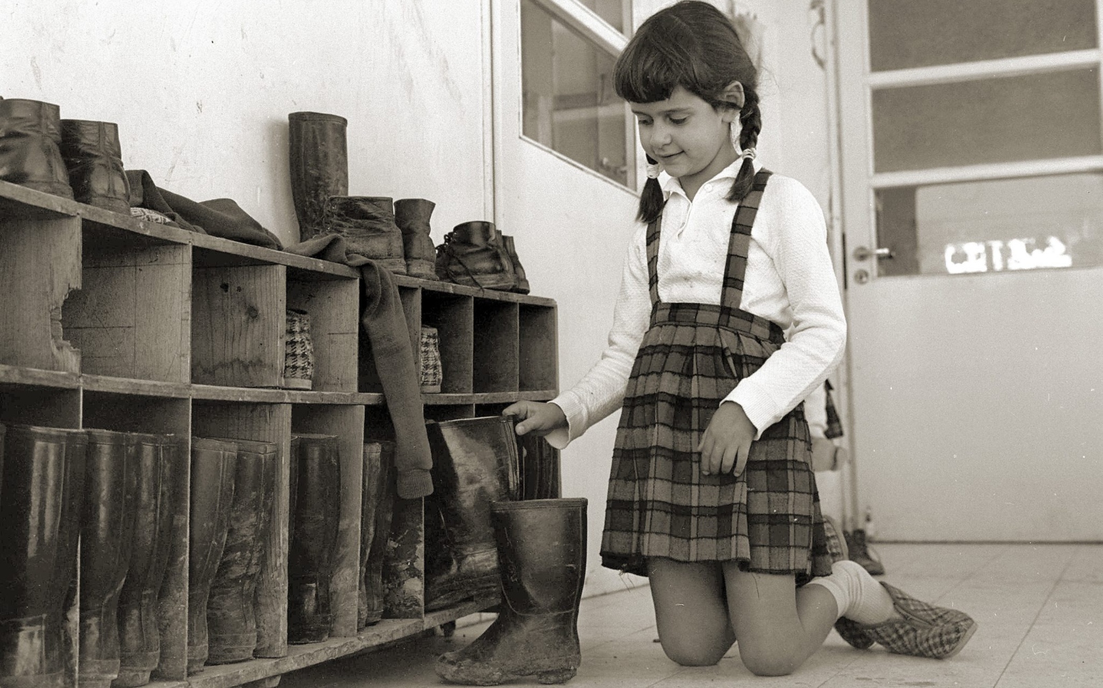 In winter on kibbutz, the boots came off and the plaid slippers went on, to keep mud out of the house. This photo was taken in 1965 by the Government Press Office.