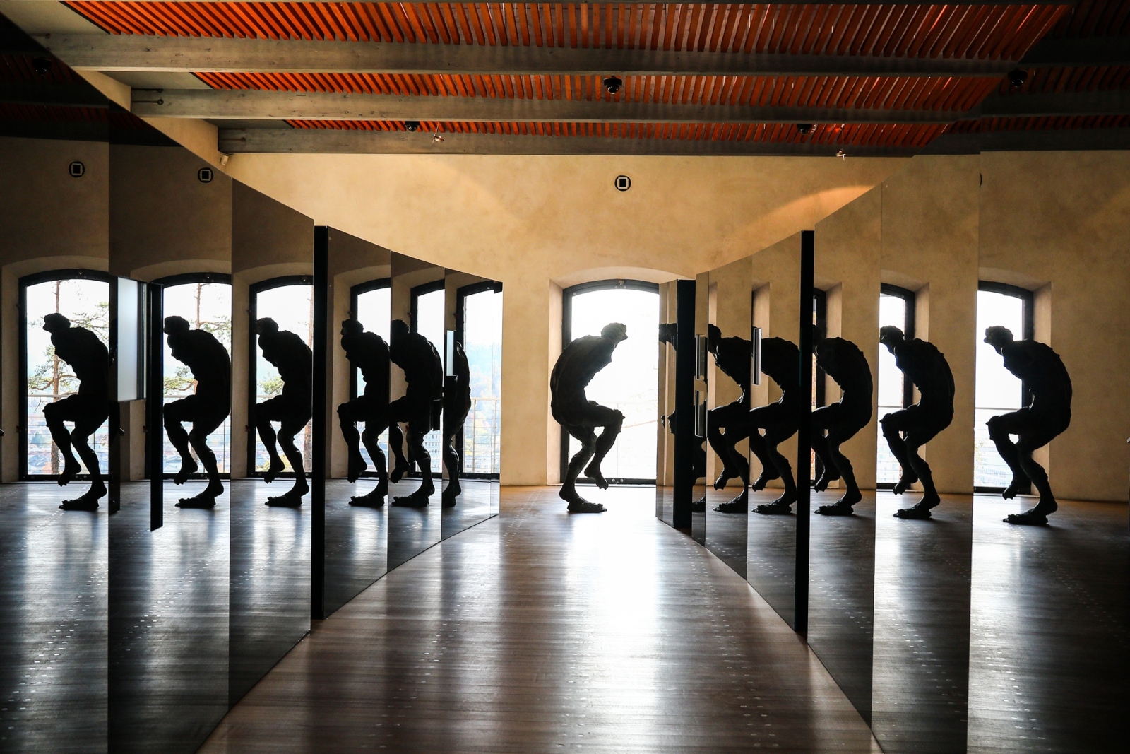 A metal statue reflects across glass display cases in a history museum in Ljubljana, Slovenia. Photo by Ilan Rogers