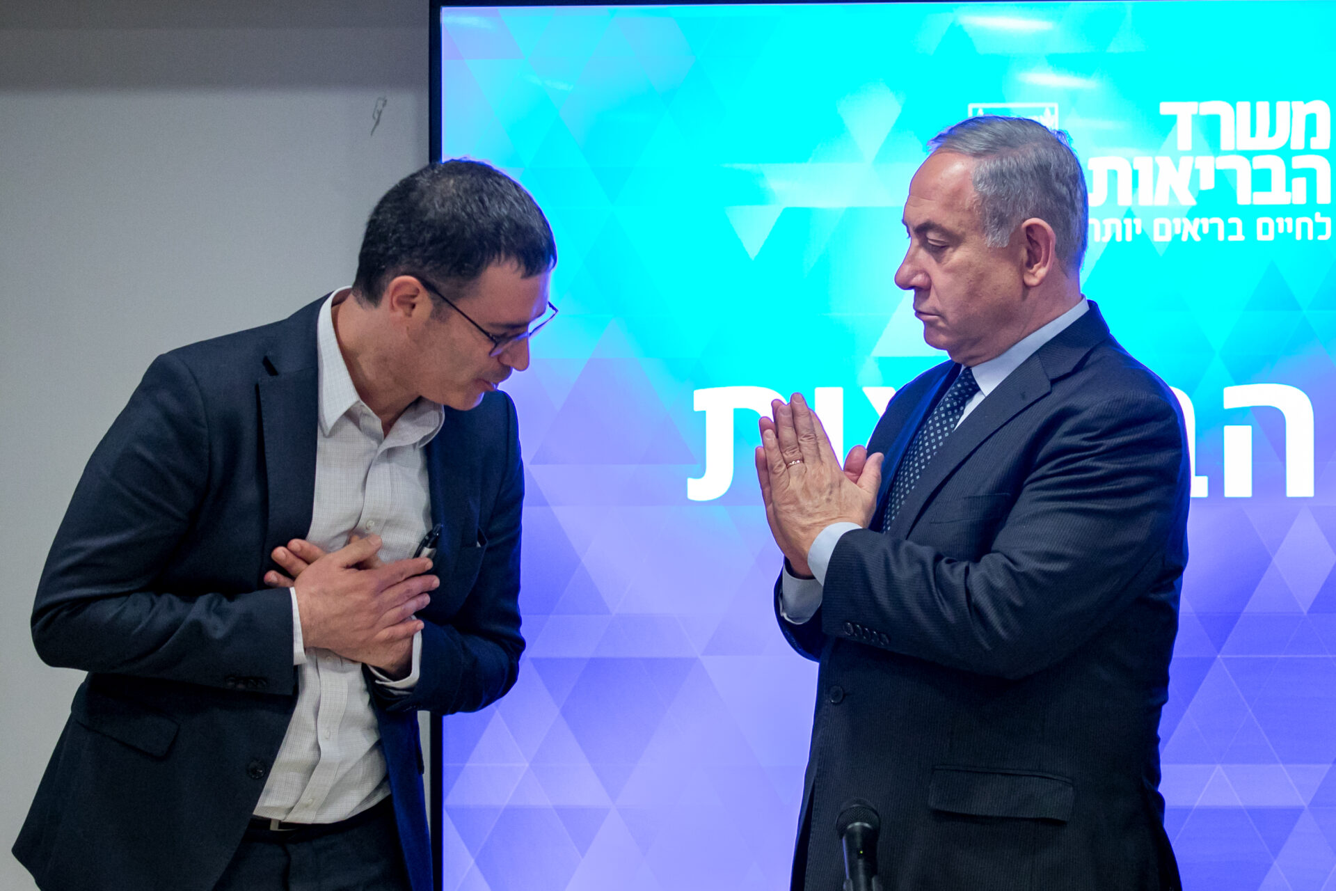 Israeli Prime Minister Benjamin Netanyahu, right, and Director General of the Ministry of Health Moshe Bar Siman Tov demonstrate how to greet one another without shaking hands due to coronavirus concerns, March 4, 2020. Photo by Olivier Fitoussi/Flash90