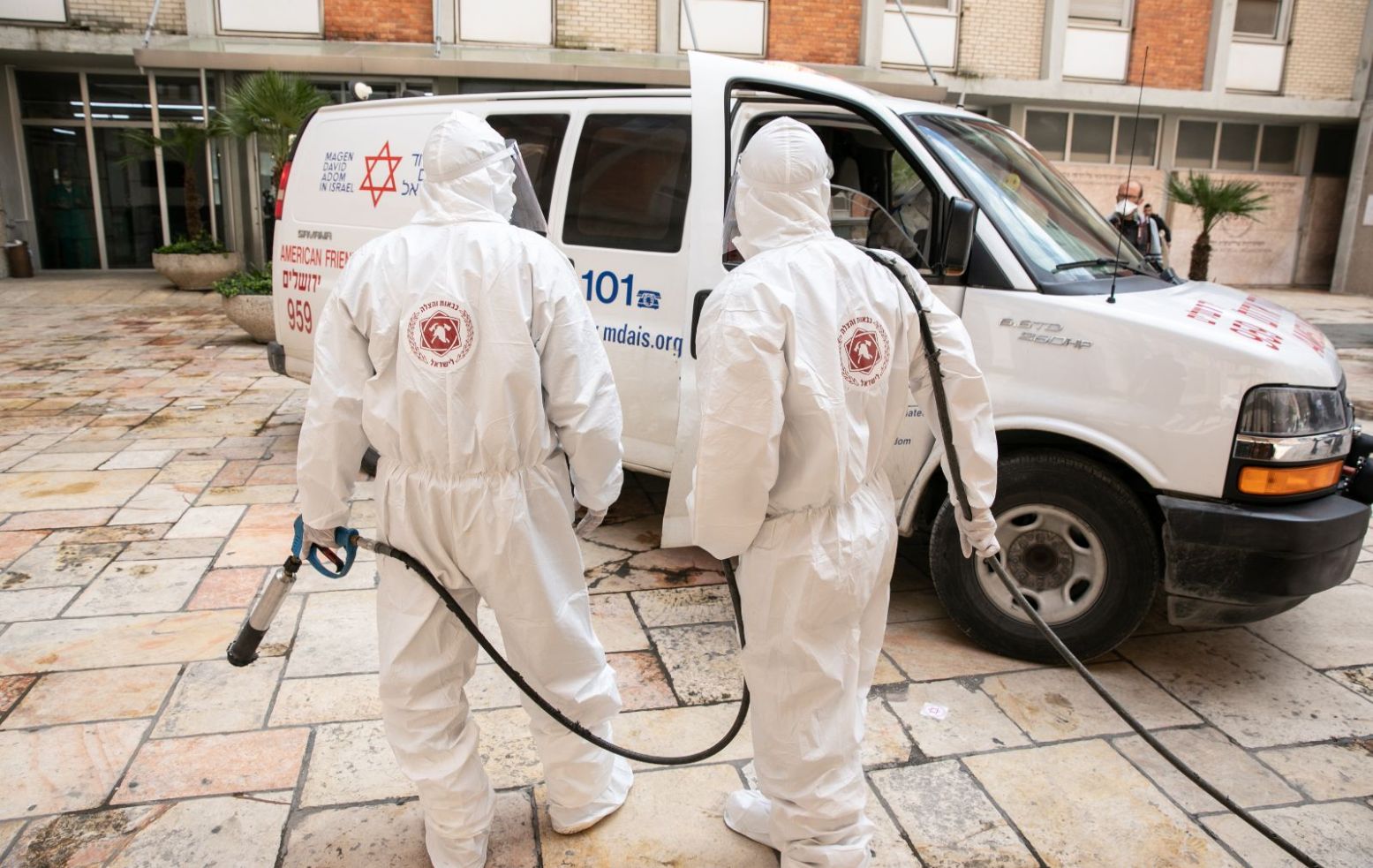 Firefighters wearing protective clothes disinfect the entrance of the emergency room of Hadassah Ein Kerem hospital in Jerusalem. Photo by Olivier Fitoussi/Flash90