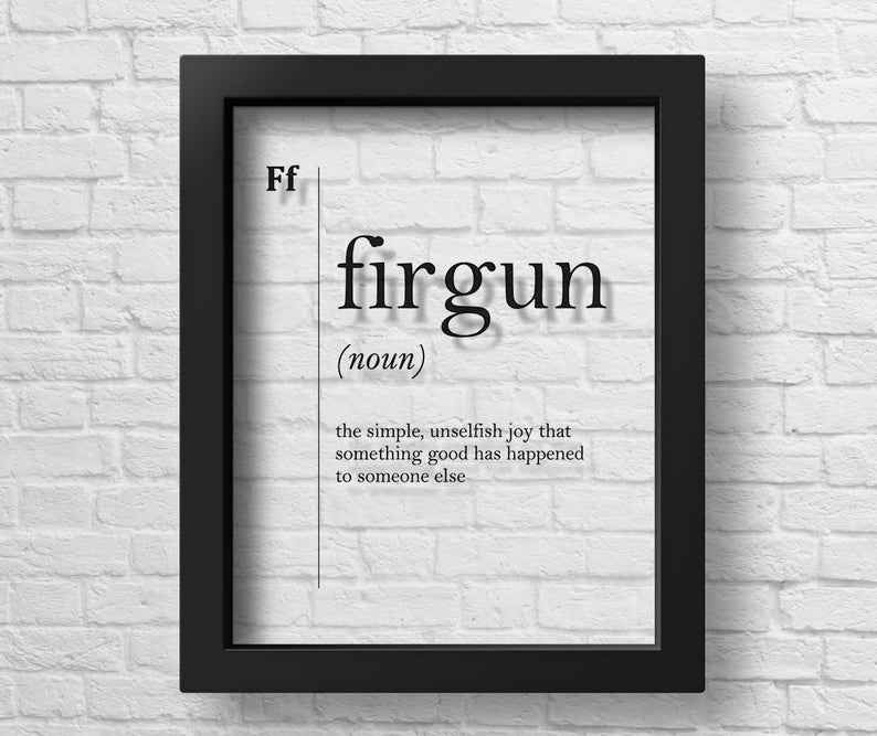 A framed print on a white brick wall displays the word firgun with its definition: the simple, unselfish joy that something good has happened to someone else.