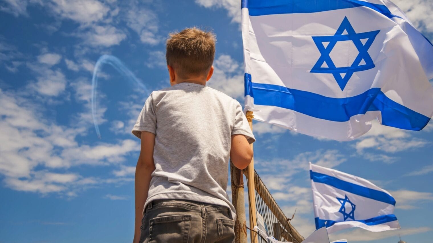 A boy watches the Israel Air Force perform the annual fly by on Independence Day from the beach. Photo by Roman Yanushevsky via Shutterstock