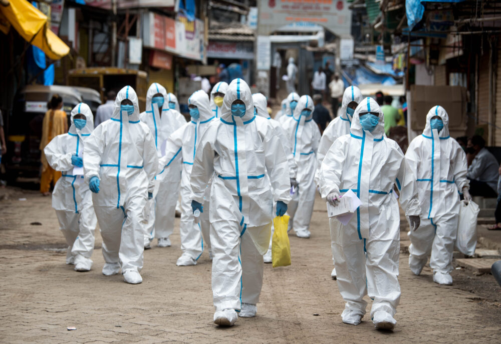 Health workers wearing PPE arrive to take part in a check up at a slum in India during the Covid-19 crisis. Photo by Shutterstock