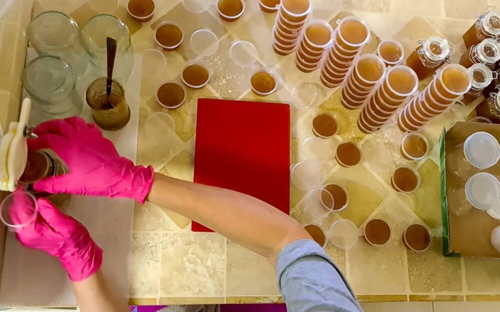 Beekeeper Miri Newcome filling and weighing containers and bottles of Neshikha raw, unprocessed honey. Screenshot: davidbrianbender.com