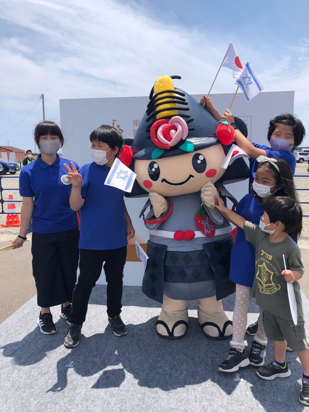 Watari residents — including a boy in an IDF t-shirt -- cheering on an Israeli Embassy official during the Olympic Torch race. Photo courtesy of Israeli Foreign Ministry