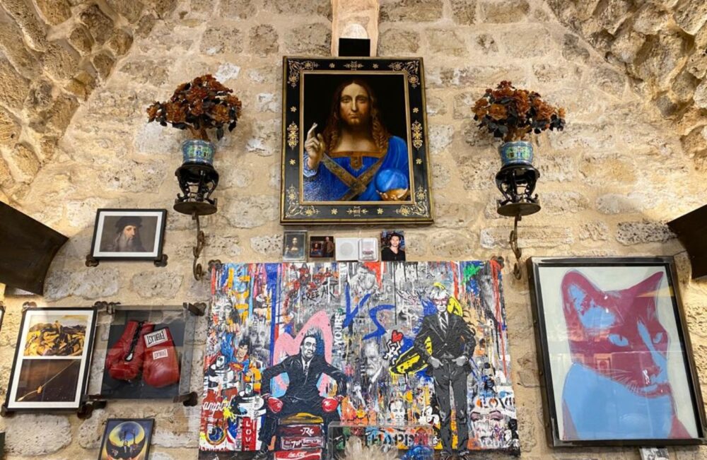 One wall of the Uri Geller Museum contains, among other items, a Salvador Dali painting (right), Yuvi’s pop art painting (center), and an Andy Harwood replica of Leonardo da Vinci’s “Salvator Mundi” with the original crystal ball above it. Photo by Abigail K. Leichman