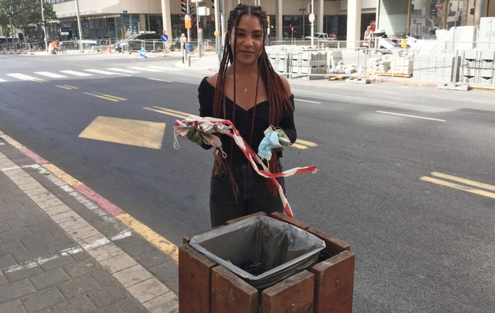 Sharona Shnayder throwing away trash she picked up on a Tel Aviv street. Photo by Diana Bletter