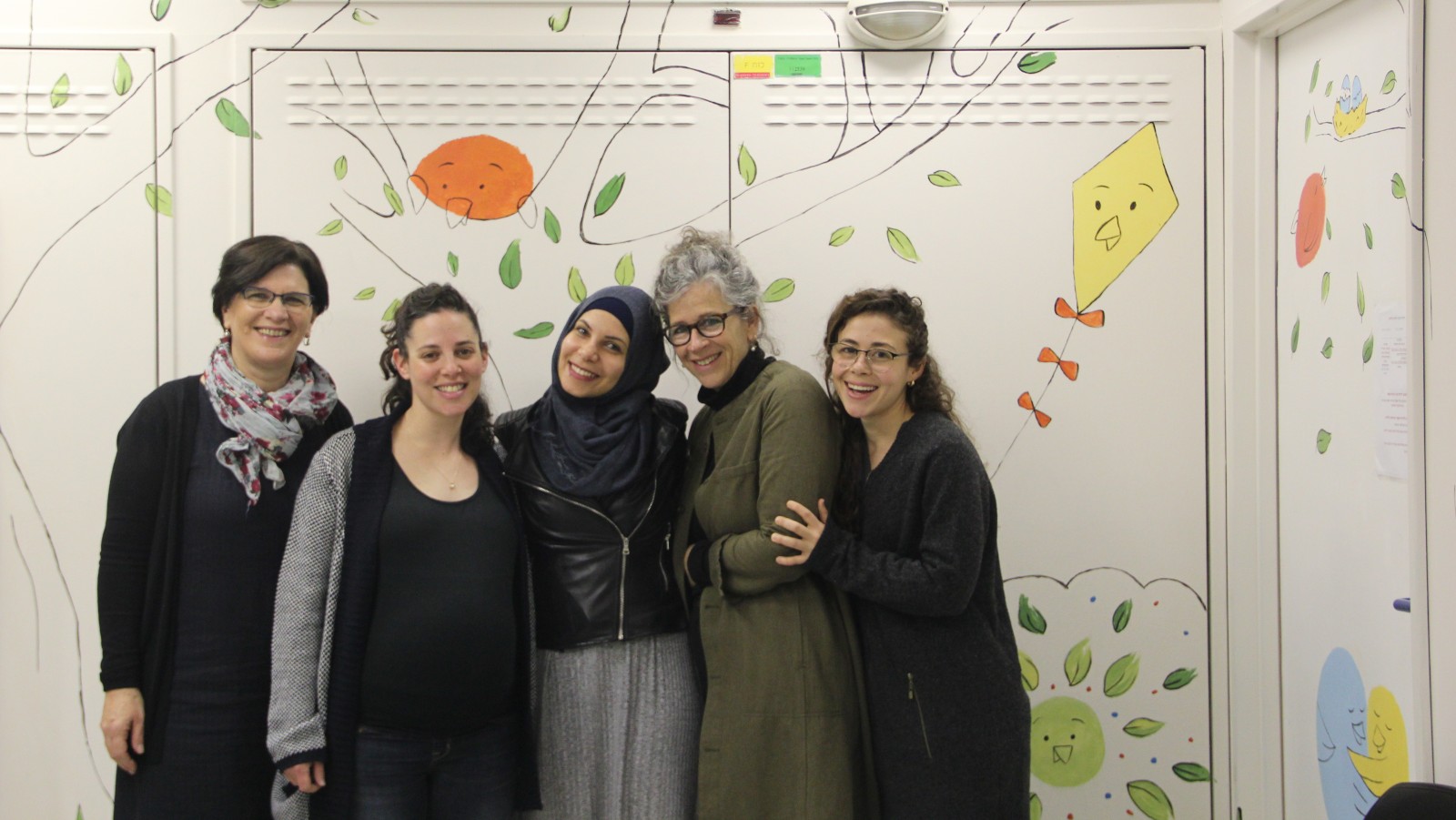 In the pediatric outpatient surgery waiting room at Hadassah Medical Center-Ein Kerem, from left, Haverut Founder & CEO Rachel Fox- Ettun, illustrator and graphic designer Naama Bernhardt, artist Alaa Edris, spiritual caregiver and artist Judy Weingrod, and Haverut educator/project manager Avital Gvaryahu Taf. The wall was a project of Haverut.