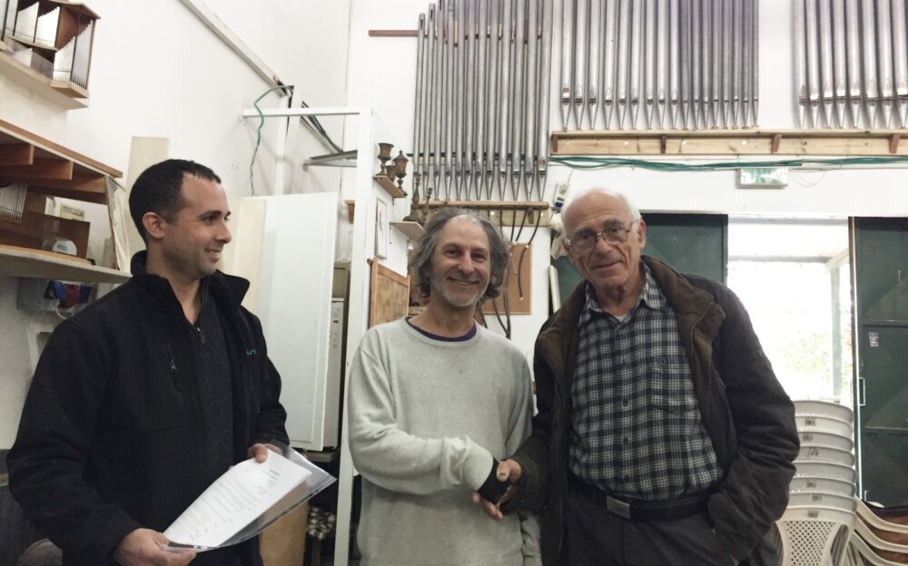 Uri Shani, center, shaking hands with Gideon Shamir, right, while attorney Yuval Turgeman looks on. Photo by Diana Bletter