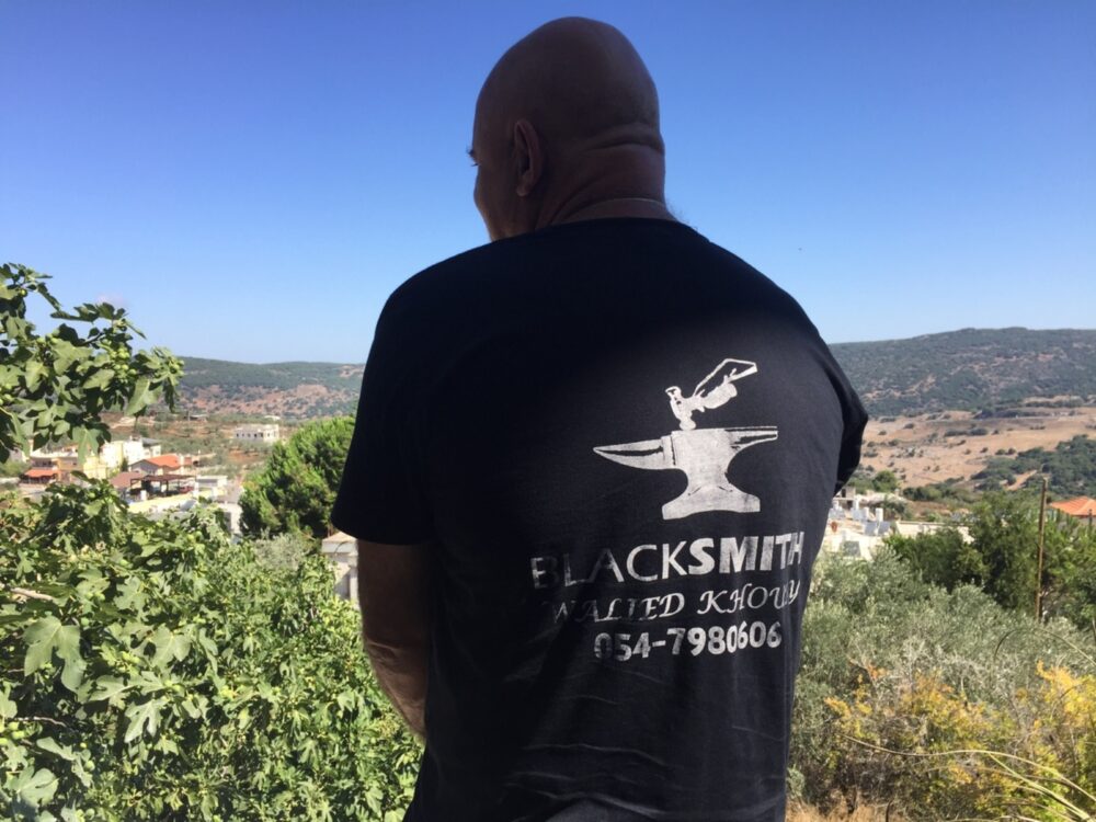 Walied Khoury on his terrace in his blacksmith T-shirt with a view of Lebanon in the distance. Photo by Diana Bletter