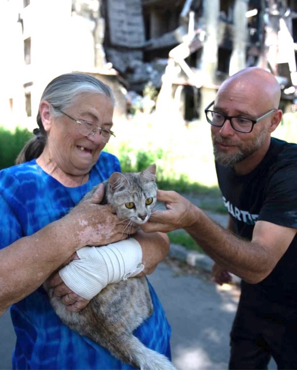 SmartAID Director Shachar Zahavi with a woman who lived in the bombed-out building seen behind them in Hostomel, Ukraine. Photo courtesy of SmartAID