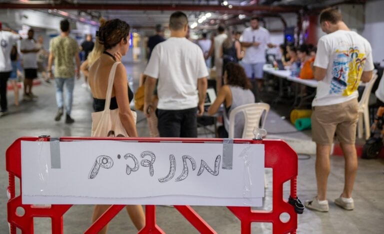 This sign at the parking garage where Eran’s Angels are working says “Volunteers.” Photo by John Jeffay