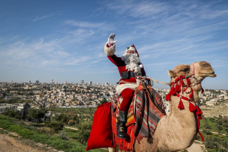 Issa Kassissieh, dressed as Santa Claus rides on a camel at Mount of Olives, overlooking the Old City of Jerusalem, ahead of the upcoming holiday of Christmas, December 4, 2023. Photo by Jamal Awad/Flash90