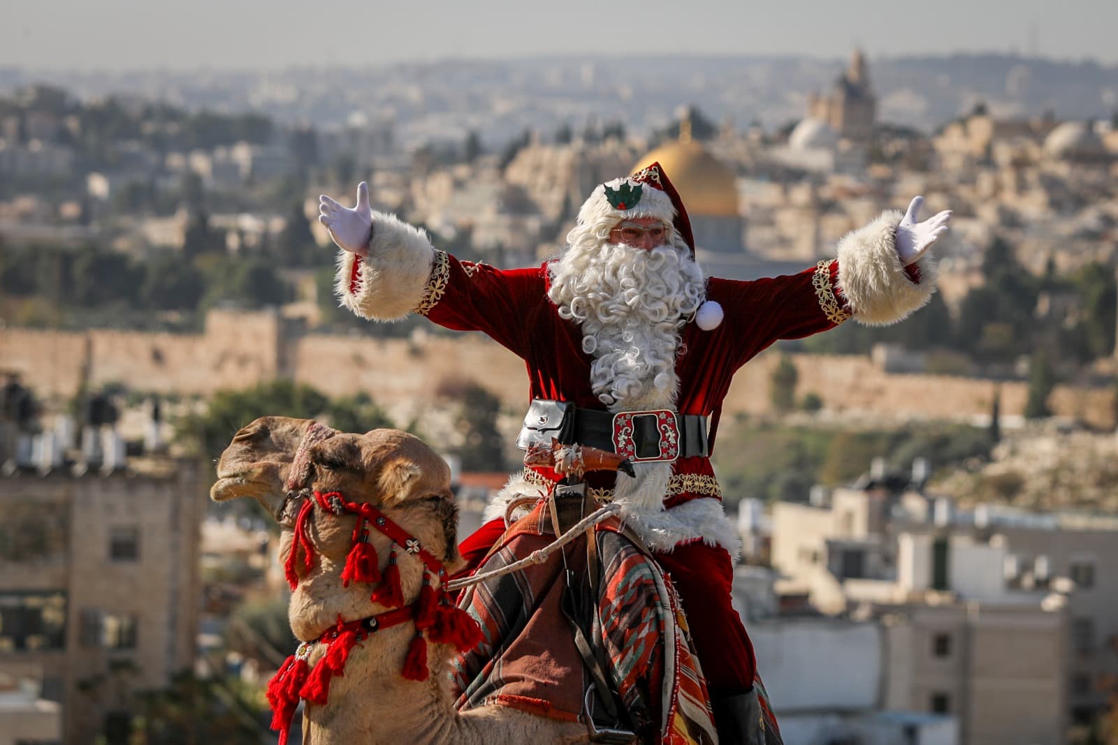 Issa Kassissieh, dressed as Santa Claus rides on a camel at Mount of Olives, overlooking the Old City of Jerusalem, ahead of the upcoming holiday of Christmas, December 4, 2023. Photo by Jamal Awad/Flash90
