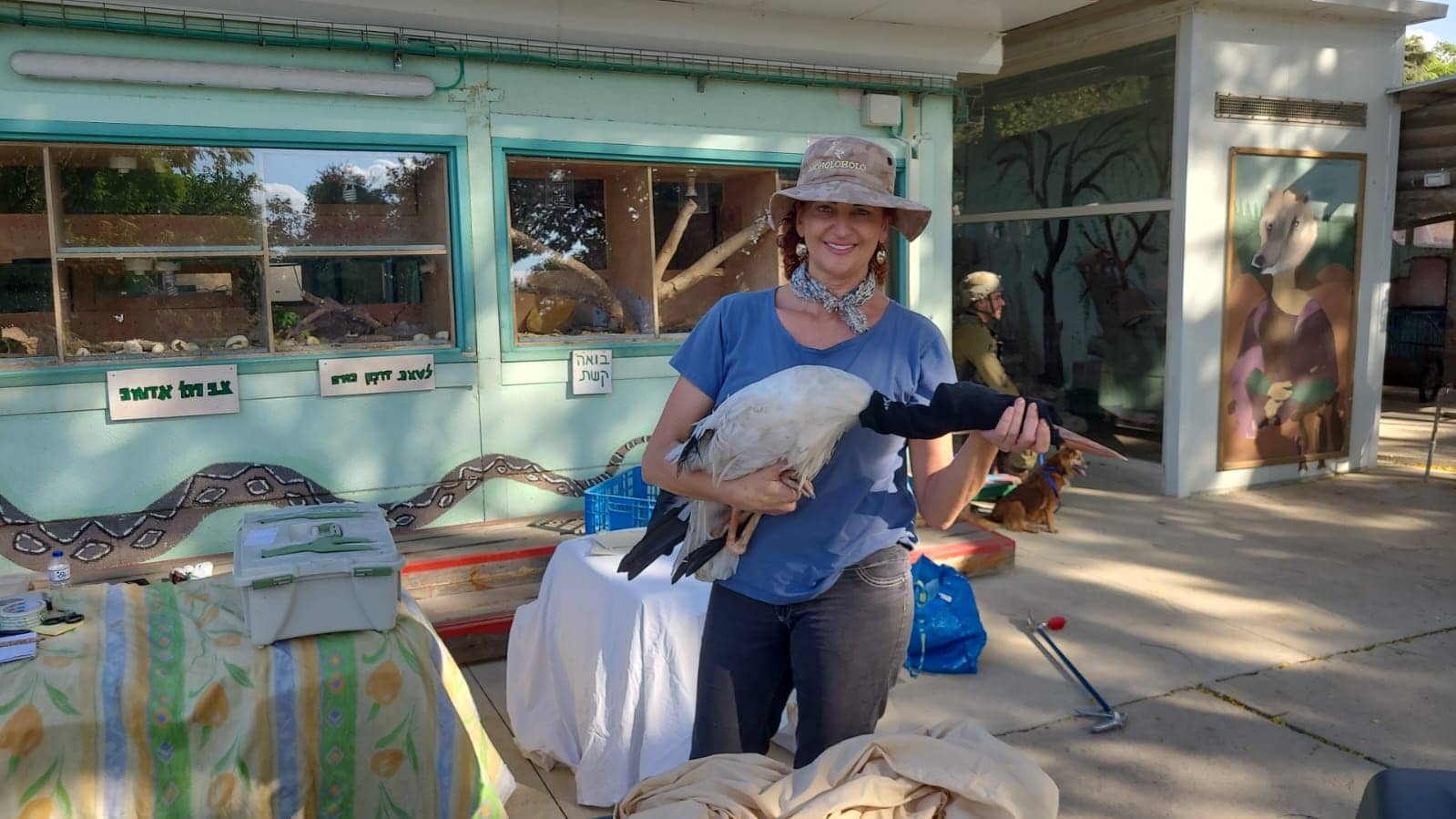 Lany Rosenberg, accompanied by soldiers, evacuates a stork from a petting zoo in Kibbutz Be’eri a few days after the kibbutz was attacked. Photo by Shachar Kara