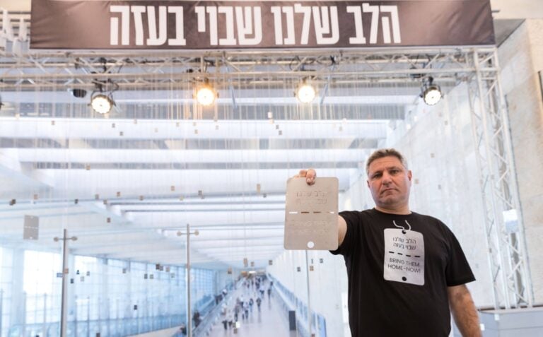 Project initiator Tamir Raicher holding a dog tag at Ben-Gurion Airport. Photo by Barak Ziv