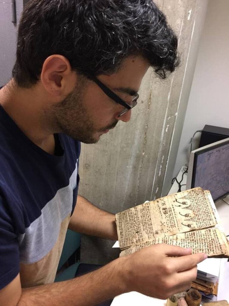 Gal Sofer holding an ancient witchcraft text. Photo by Sarah Oppenberg/Ben-Gurion University