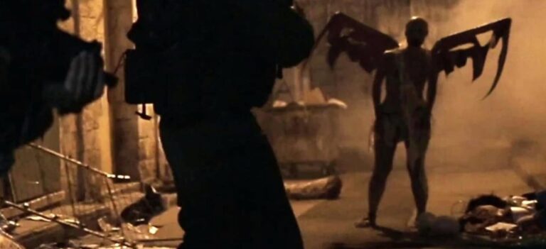 A dark, smoky scene shows a humanoid figure with tattered wings standing among debris, while armed figures in the foreground face it. The atmosphere appears tense and eerie.
