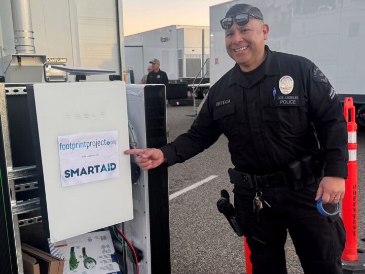 A Los Angeles police officer points to a Tesla mobile solar microgrid set up by SmartAID with its partner Footprint to support first responders and community relief hubs. Photo courtesy of SmartAID